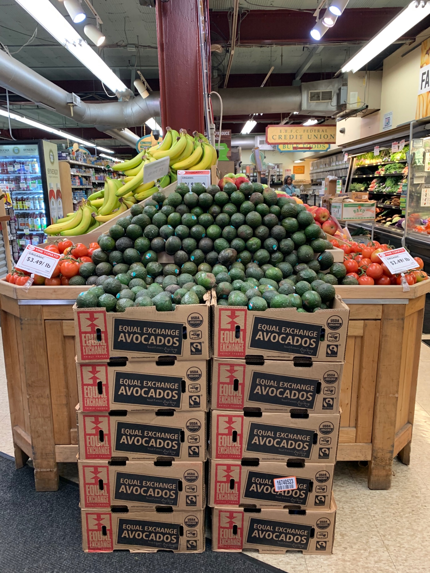 Pyramid of Equal Exchange organic avocados stacked between vine tomatoes and bananas